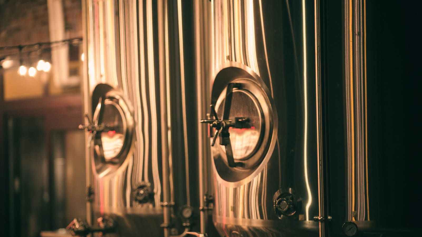Stainless steel brewing tanks glowing in warm amber light
